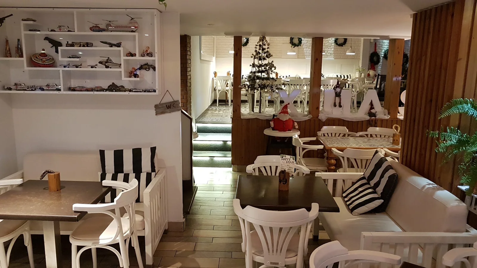 Inside Pingouino: white chairs, striped cushions and a shelf of vintage toy cars and planes